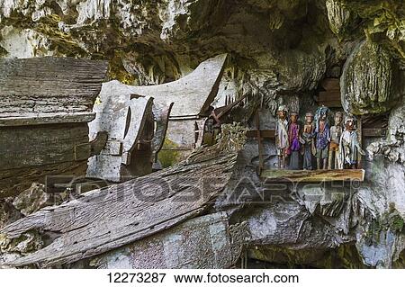 Stock Photo - Wooden coffins in a burial cave and graves made in the rock with wood-carved effigies of the deceased, called Tau tau, Tampangallo, Toraja Land, South Sulawesi, Indonesia. Fotosearch