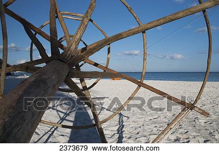 Stock Photo - Wooden frame of a beach umbrella laying on the sand; Tulum, Mexico. Fotosearch
