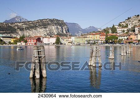 Picture - Wooden pilings in the water in Lake Garda with buildings along the water's edge; Malcesine, Verona, Italy. Fotosearch