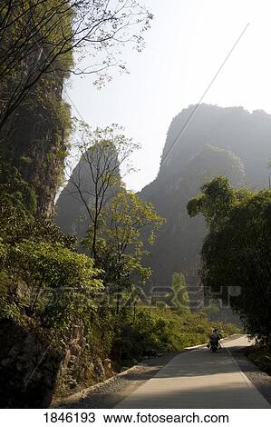 Stock Image - Yangshuo, China; Person Walking Down Country Road. Fotosearch