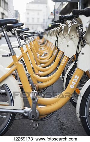 Stock Image - Yellow and white bicycles parked in a row; Milan, Lombardy, Italy. Fotosearch