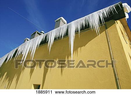 Stock Image - Yellow Building With Icicles Hanging Off The Roof. Fotosearch