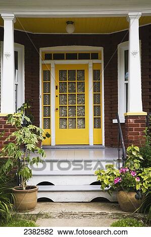 Yellow Entrance Door And Porch On A Residential Red Brick Home