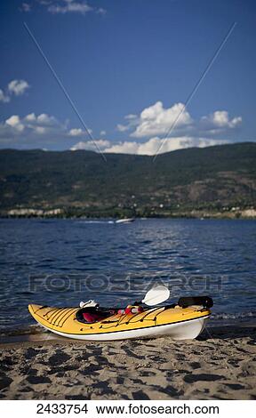 Picture - Yellow kayak on beach shore; British Columbia, Canada. Fotosearch