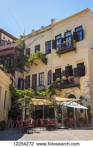 Stock Image - Yellow residential building and restaurant patio; Chania, Crete, Greece. Fotosearch