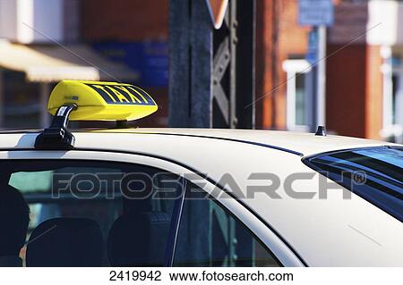 Stock Image - Yellow taxi sign on top of a white car; Hamburg, Germany. Fotosearch