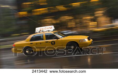 Stock Image - Yellow taxi speeding through the streets; New York City, New York, United States of America. Fotosearch