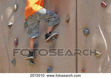 Stock Image - Young Boy Climbing Rock Wall At Playground. Fotosearch