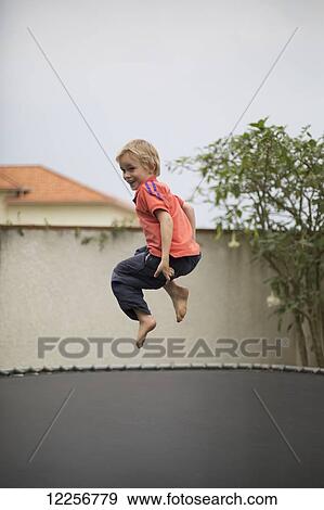 Stock Photo - Young boy jumping on a trampoline; Kigali, Rwanda. Fotosearch