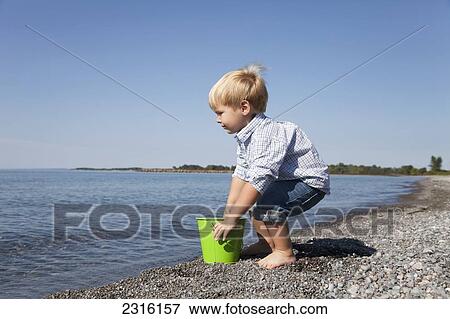 Young Boy Playing With A Pail On The Beach By Lake Ontario; Ontario Canada View Large Photo Image Stock Photo - Young Boy Playing With A Pail On The Beach By Lake Ontario; Ontario Canada. Fotosearch