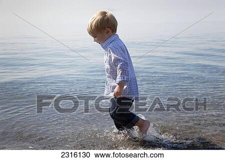Stock Image - Young Boy Running Through The Waves At The Beach By Lake Ontario; Ontario Canada. Fotosearch