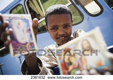 Stock Image - Young boy selling religious cards by the roadside; Gondar, Ethiopia. Fotosearch
