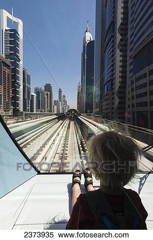 Stock Photography - Young boy sitting at the front of metro train as it travels through the business district of Dubai; Dubai, United Arab Emirates. Fotosearch