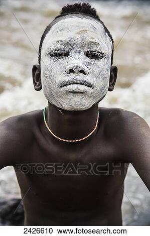 Stock Image - Young boy with traditional painted face, paint made from natural ground river stones, Omo region, Southwest Ethiopia; Kibish, Ethiopia. Fotosearch