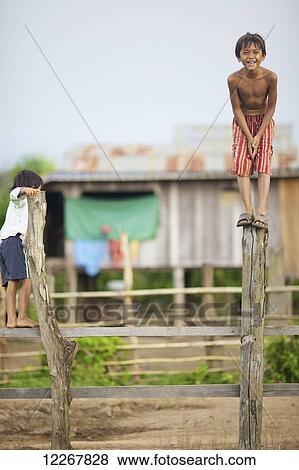 Young boys standing on wooden fence posts; Mondulkiri, Cambodia View Large Photo Image Stock Photo - Young boys standing on wooden fence posts; Mondulkiri, Cambodia. Fotosearch