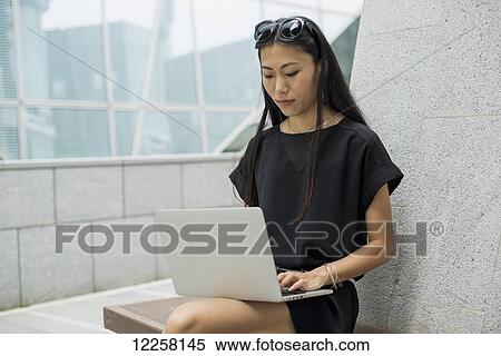 Stock Photography - Young businesswoman working on her laptop computer; Xiamen, China. Fotosearch