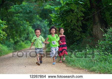 Young children running down a dirt road; Battambang, Cambodia View Large Photo Image Picture - Young children running down a dirt road; Battambang, Cambodia. Fotosearch
