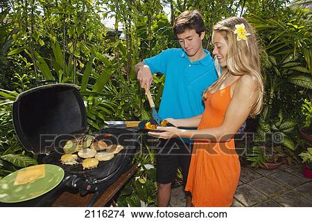 Picture - Young couple at an oudoor barbeque lunch in a Hawaiian garden.. Fotosearch