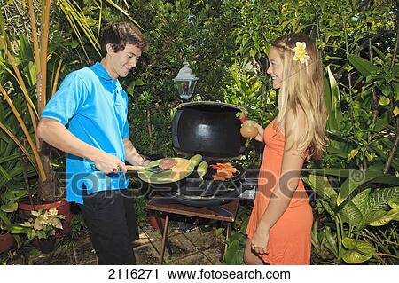 Stock Image - Young couple at an oudoor barbeque lunch in a Hawaiian garden.. Fotosearch