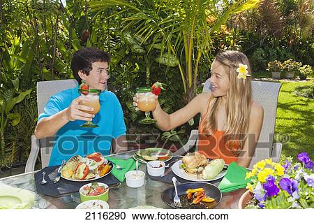 Stock Image - Young couple at an oudoor barbeque lunch in a Hawaiian garden.. Fotosearch