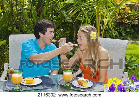 Stock Image - Young couple at an oudoor barbeque lunch in a Hawaiian garden.. Fotosearch