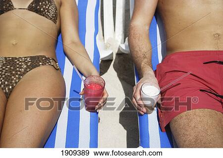 Stock Photo - Young Couple Drinking Cocktails On Sunloungers At Beach, Mid Section, Mayan Riviera, Yucatan Peninsular, Quintana Roo State, Mexico. Fotosearch