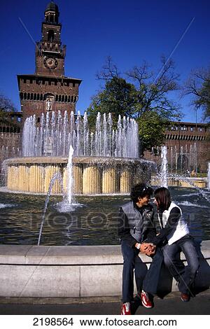 Picture - Young Couple Sitting Beside Fountain At Castello Sforzesco, Holding Hands, Love, Romantic. Milan, Italy. Fotosearch