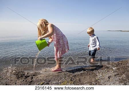 Stock Photography - Young Girl And Her Brother Playing On The Beach By Lake Ontario; Ontario Canada. Fotosearch