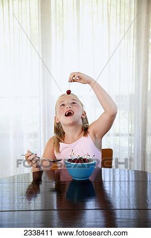 Stock Image - Young Girl At Home Eating Cherries; San Francisco, California, Usa. Fotosearch