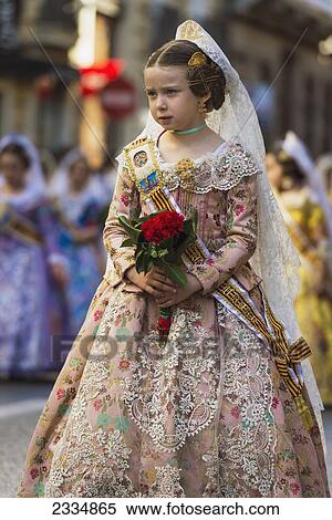 Stock Photography - Young Girl Dressed Up In Traditional Casal Faller Dress In Procession With Flower Offering For Virgin De Los Desamparados At Fallas Festival; Valencia, Spain. Fotosearch