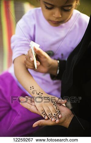 Stock Photo - Young girl getting henna on her hand; Taif, Saudi Arabia. Fotosearch