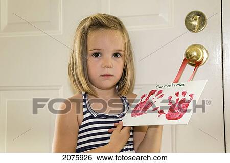 Stock Photograph - Young Girl Holding An Image Of Her Handprints; Ontario Canada. Fotosearch