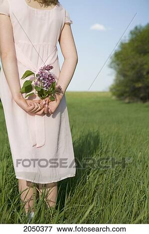Young Girl Holding Flowers Behind Her Back In A Field View Large Photo Image Stock Photo - Young Girl Holding Flowers Behind Her Back In A Field. Fotosearch