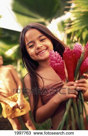 Stock Image - Young Girl Holding Ginger Flowers With Cropped Boy In Background Lush Jungle Setting. Fotosearch