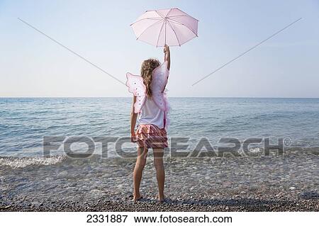 Stock Photo - Young Girl Holding Her Pink Parasol Over Her Head On The Shore Of Lake Ontario; Whitby Ontario Canada. Fotosearch
