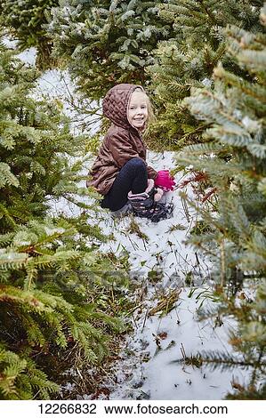 Stock Image - Young girl in amongst the trees at a Christmas tree farm; Stoney Creek, Ontario, Canada. Fotosearch