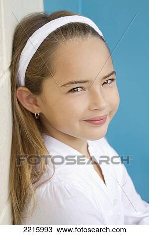 Young girl in front of a blue wall, wearing a white shirt and headband. View Large Photo Image Stock Image - Young girl in front of a blue wall, wearing a white shirt and headband.. Fotosearch