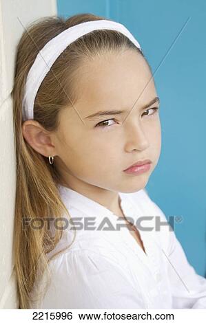 Young girl in front of a blue wall, wearing a white shirt and headband. View Large Photo Image Stock Photograph - Young girl in front of a blue wall, wearing a white shirt and headband.. Fotosearch