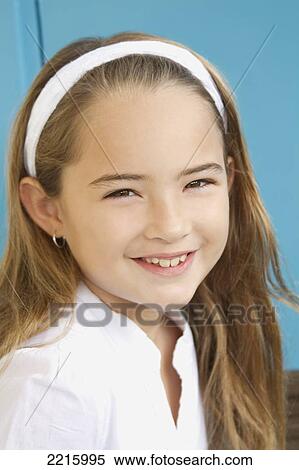 Stock Photography - Young girl in front of a blue wall, wearing a white shirt and headband.. Fotosearch