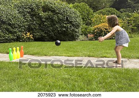 Stock Image - Young Girl Playing Bowling In The Garden; Ontario Canada. Fotosearch