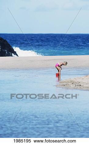 Stock Photography - Young Girl Playing In Ocean Water On Beach With Bucket And Pail.. Fotosearch