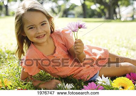 Stock Photo - Young Girl Playing With Flowers In The Grass.. Fotosearch
