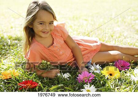 Stock Photo - Young Girl Playing With Flowers In The Grass.. Fotosearch