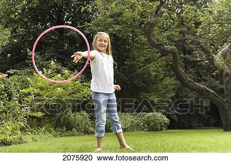 Stock Image - Young Girl Playing With Her Hula Hoop In The Garden; Ontario Canada. Fotosearch