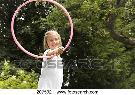 Stock Image - Young Girl Playing With Her Hula Hoop In The Garden; Ontario Canada. Fotosearch