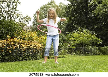 Stock Photo - Young Girl Playing With Her Hula Hoop In The Garden; Ontario Canada. Fotosearch