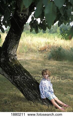Stock Image - Young Girl Sitting In Walnut Tree. Fotosearch