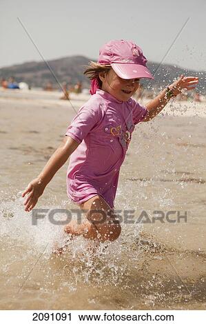 Stock Image - Young Girl Splashing Through The Water At The Beach; Tarifa, Cadiz, Andalusia, Spain. Fotosearch