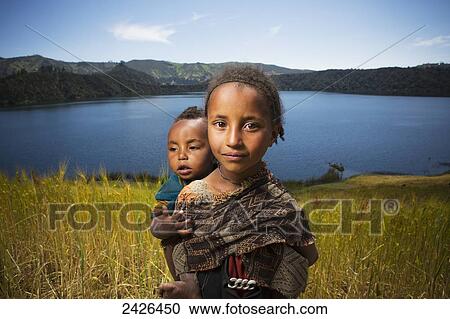 Young girl with baby on her back in wheat field, Wenchi crater and lake, to the West of Addis Ababa; Ethiopia View Large Photo Image Stock Image - Young girl with baby on her back in wheat field, Wenchi crater and lake, to the West of Addis Ababa; Ethiopia. Fotosearch