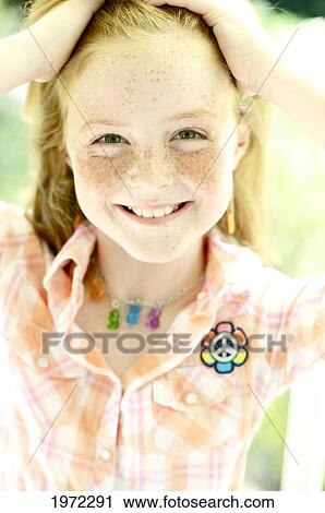 Stock Image - Young Girl With Red Hair And Freckles Pulls Back Her Hair.. Fotosearch